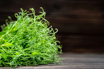 Cutted microgreen pea sprouts on old wooden table. Vegan and healthy eating concept. Growing sprouts.