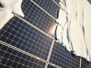Close up surface of a house roof covered with solar panels in winter with snow on top. Energy efficiency and maintenance concept.