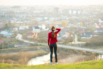 Young woman standing outdoors enjoying city view. Relaxing, freedom and wellness concept.