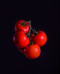 Red grapola tomato levitating on a dark background.