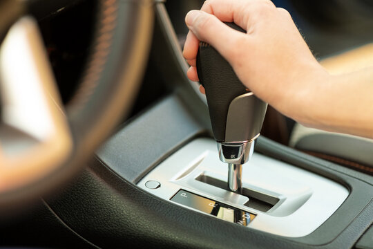 Close up of woman driver holding her hand on automatic gear shift stick driving as car.