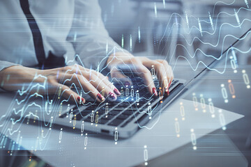 Multi exposure of woman hands typing on computer and financial graph hologram drawing. Stock market...