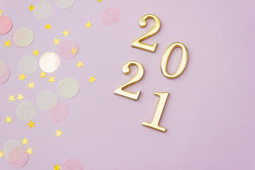 Golden number 2021 on pink background decorated with pastel and starry confetti. New Year celebration concept.