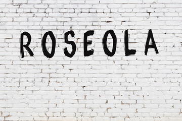 Inscription roseola painted on white brick wall