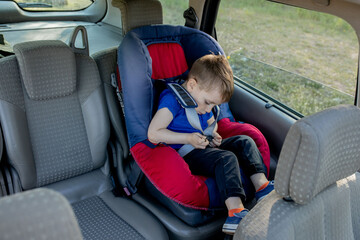 Little boy buckled up with seatbelt inside the car. Vehicle and transportation concept.