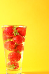 Strawberries in ice water in a glass on a sunflower background. Summer cocktail. High quality photo