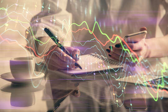 Double exposure of financial graph sketch hologram and woman holding and using a mobile device. Stock exchange concept.