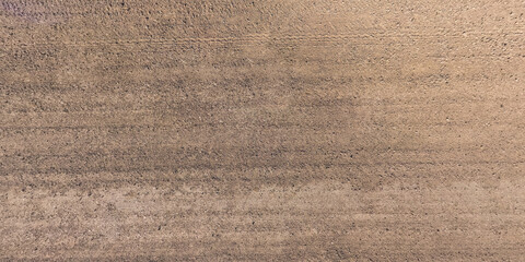 view from above on surface of gravel road with car tire tracks