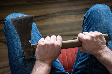 A man squeezing an ax in his knees. The concept, Domestic violence, social problems, crime