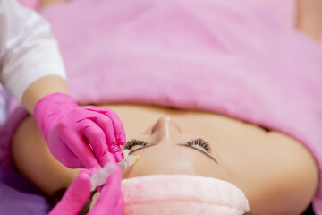 The doctor cosmetologist makes the Rejuvenating facial injections procedure for tightening and smoothing wrinkles on the face skin of a beautiful, young woman in a beauty salon.Cosmetology skin care.