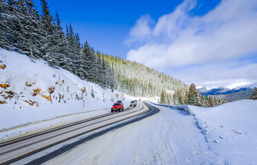 View of mountain highway in Colorado, USA, in winter with driving cars and sky in background