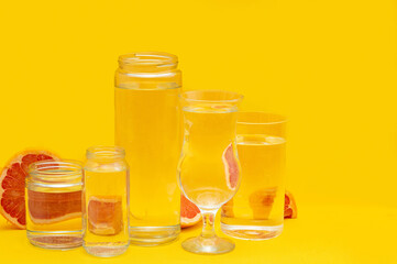 Grapefruit distorted through glasses with water. Summer concept. Yellow background