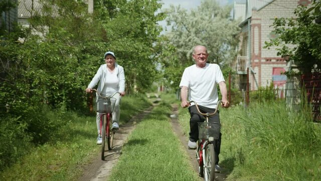 healthy lifestyles, older man and woman having fun cycling together during family walk outside city on sunny summer day at weekend