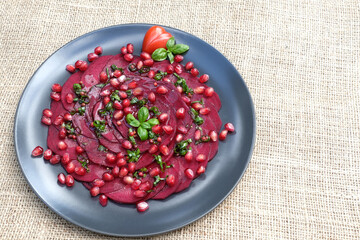 Beetroot carpaccio with pomegranate, basil leaf and cherry tomatoes.