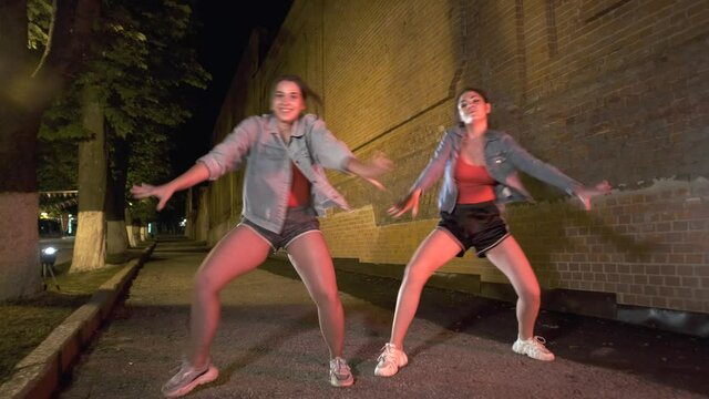 two young girls dance street dance in a city park in the evening. Youth subculture. Contemporary choreography. Gimbal shot
