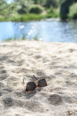 Sand beach in the river and sunglasses, rural tourism concept.