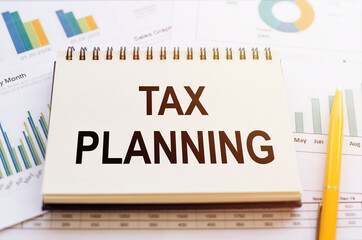Tax planning word written by notepad on financial graphs with yellow pen