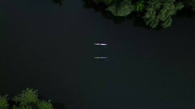 Aerial drone shot of two men riding a cayaks on small river, bird eye view 4k footage