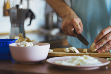 a young chef cuts mushrooms and cooks chicken. Cooking julienne, prepare meat at home
