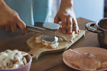 a young chef cuts mushrooms and cooks chicken. Cooking julienne, prepare meat at home