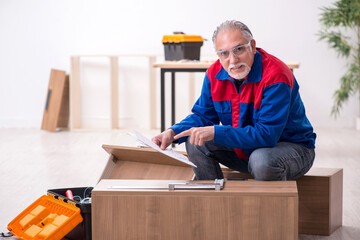 Old male carpenter working indoors