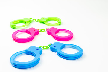 The toy handcuffs are available in green, pink and blue. On a white background.