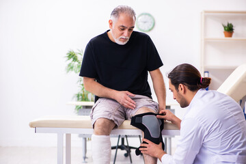 Old injured man visiting young male doctor traumatologist