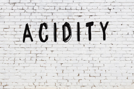 Inscription acidity painted on white brick wall