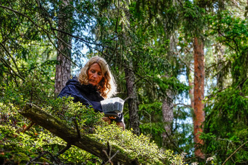 Naklejka na ściany i meble Stockholm, Sweden A woman in the forest picks forest blueberries.