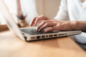 Close up hands of woman using laptop computer working and searching online information with blurry background. copy space of technology business and social distancing concept