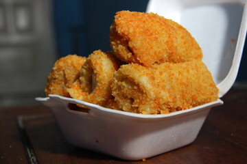 crispy roll cake with egg and sausage flavor. snacks with white and pastic containers on a wooden table