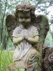 Closeup of weathered statue of baby cherub on grave