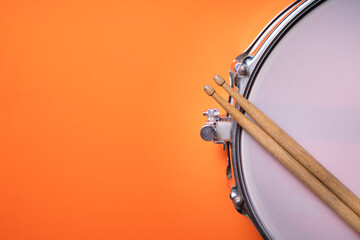 Drum stick and drum on orange table background, top view, music concept © tatomm