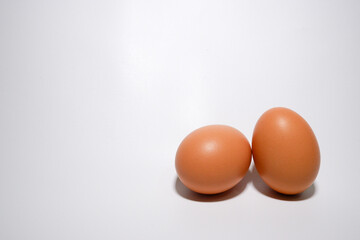 Two eggs that placed on a white background. One egg is layed down, and the other one is  standed (Side View)