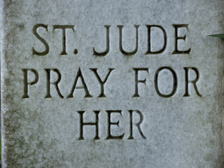 Closeup of headstone inscribed with text "St Jude Pray for Her"