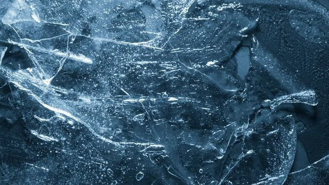 Close-up of melting ice texture. Studio shot close-up of the blue surface of cracked melting ice in time lapse.