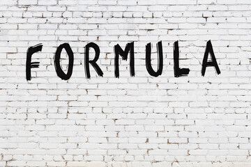 Inscription formula painted on white brick wall