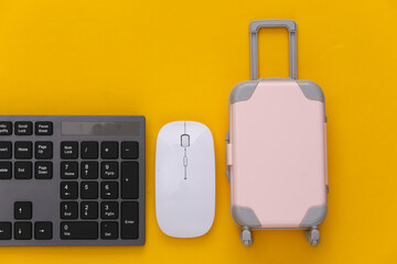 Travel concept. PC keyboard and mini travel luggages on yellow background. Top view