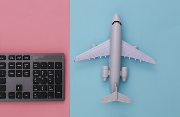 Travel concept. PC keyboard and air plane on pink blue background. Top view