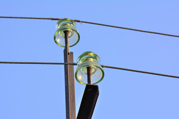 Fototapeta premium A garland of insulators on electric wires of a metal high-voltage support.