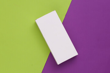 Fototapeta premium White packing box on purple green background. Minimalism. Top view