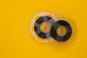 Audio magnetic tape. Two film reel on yellow background. Top view. Retro style. 80s