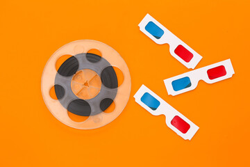 Film reel and anaglyph 3D glasses on yellow background. Entertainment industry. Cinema. Top view