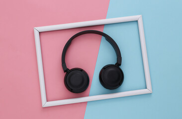 Black stereo headphones on a pink-blue background with a white frame. Top view.
