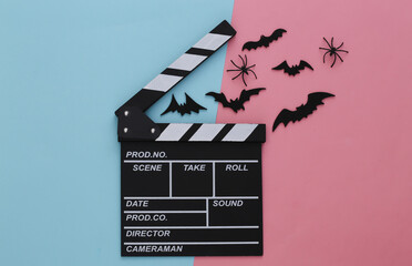 Horror movie, halloween theme. Movie clapperboard and flying decorative bats, spiders on pink blue...