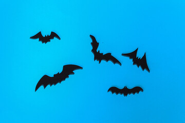 Halloween background, decorations and scary concept. Spiders and black bats fly over blue bright background