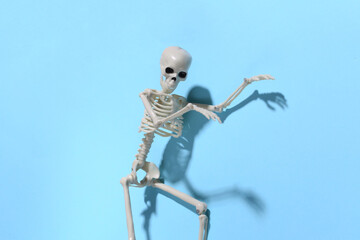 The skeleton is sneaking against a bright blue background. Halloween concept