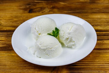 Vanilla ice cream in white plate on a wooden table