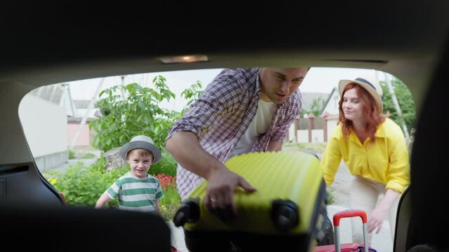 family trip, a young happy couple with their beloved male child luggage in the trunk for a trip while traveling by car during summer vacation