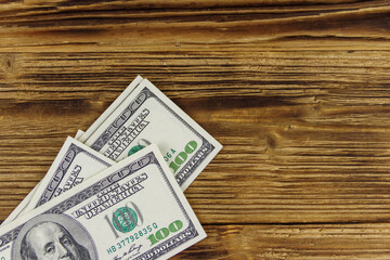 Stack of one hundred dollars bills on wooden desk